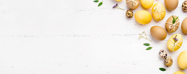 Festive Easter background. Easter eggs with flowers on a white table. Flat lay, place for text.