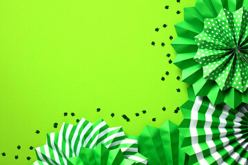 Frame of green paper fans and confetti on green background. Happy Saint Patrick's Day concept. Greeting card template, banner mockup