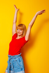 Woman standing with arms up on yellow color background