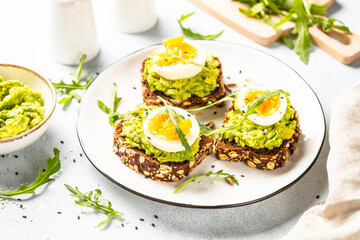 Avocado sandwich. Whole grain bread with avocado and boiled eggs with arugula. Close up image.