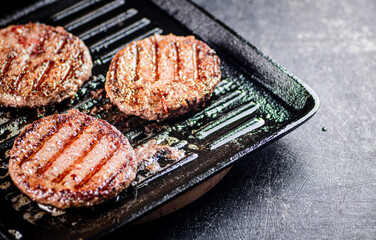 Cooking a delicious grilled burger on a pan with oil bubbles.