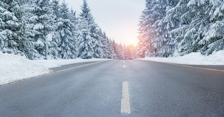 winter landscape with asphalt road,forest, sun and blue sky.