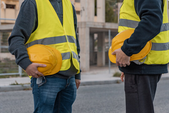 Detalle de dos trabajadores de obra, irreconocibles, con los cascos de seguridad en la mano, en el descanso del trabajo.