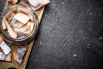 Salted herring in a glass jar on a cutting board. 