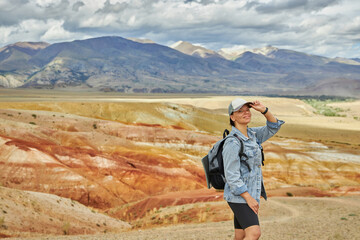 woman tourist in jeans jacket stands against backdrop of landscape on summer day. Sights of Russia, Siberia and Altai Republic, mars field. Tourism, travel and adventure. Kosh-agach, Chagan-Uzun