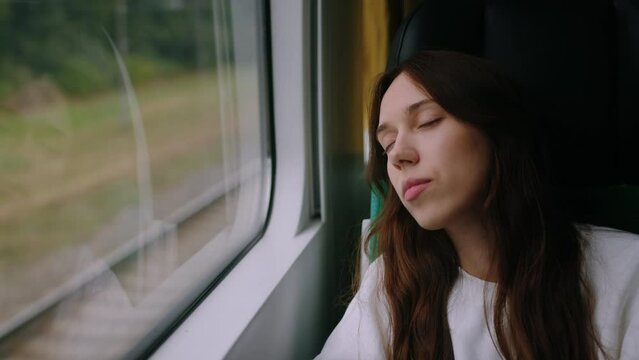 Close-up of the face of a sleeping young woman in a train carriage. A long journey