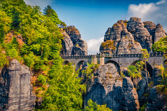 Lots of tourists on the top of cliff in Saxon Switzerland National Park. Sunny morning view of Bastei bridge, Germany, Saxony, Europe. Traveling concept background.