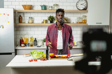 African man filming cooking vlog. Happy man filming his blog about healthy food at home