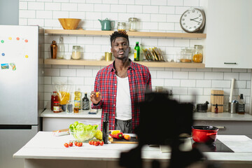 African man filming cooking vlog. Happy man filming his blog about healthy food at home