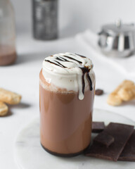 Mocha latte with whipped cream in a can shaped glass, iced mocha with foam and chocolate syrup