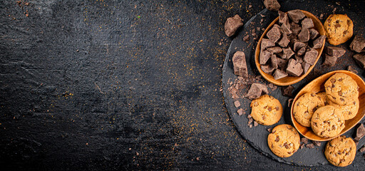 Cookies with pieces of milk chocolate on a stone board. 