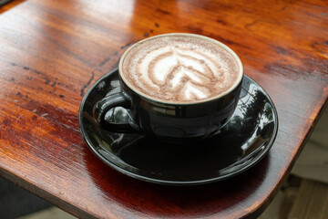 latte art coffee drink on a wooden table inside the cafe