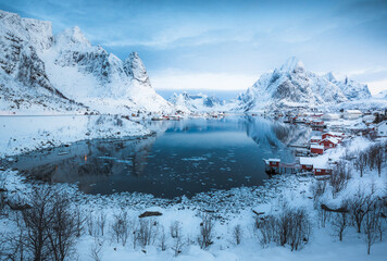 Morning sunrise in Reine, unbelievable view on small fishing village in Lofoten, Norway, Epic snowy mountains and red cabins with water, beautiful background picture from wild nature 