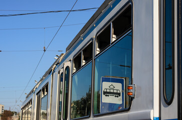 Upper part of an old tram (streetcar) with open vents and sign "Tram Stop" reflected in the glass, angled view, close-up