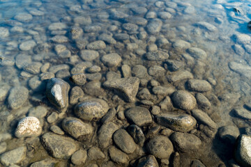 Middle size stones washed by transparent river water on sunny day. Nature details. Environment concept.