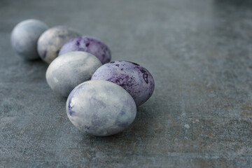 Easter concept in minimalist style. Easter eggs painted in trendy cosmic colors laid out on dark textured background. Selective focus