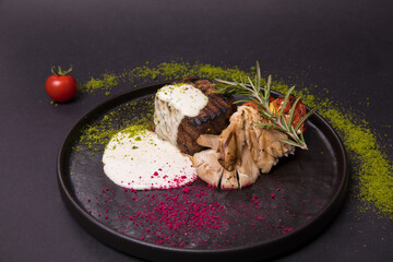 fried pork with mushroom and cream sauce, microgreens in a black plate on a dark background