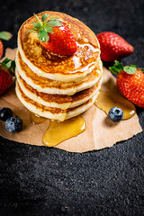 A pile of pancakes with berries and honey. 