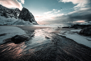 Unbelievable conditions in Kvalvika beach Lofoten, Norway. Playing lights, sun with clouds with mountains, amazing epic scenery during sunset  - obrazy, fototapety, plakaty