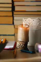 Notebook, pen, tablet, reading glasses, books, phone, candle, bowl of biscuits and cup of tea on the table. Selective focus.