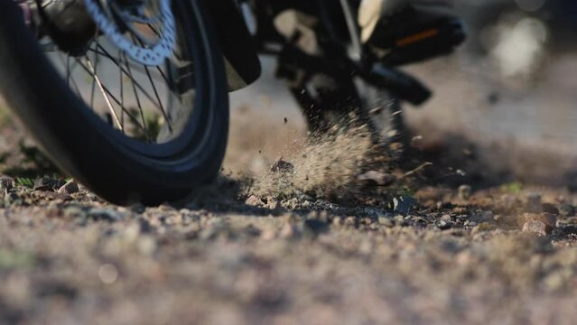 Bicycle drifting full speed in slow motion on rocky ground.