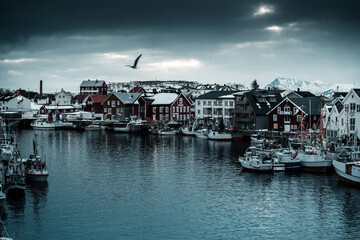Iconic view on red cabins in Hamnoy in Norway Lofoten during winter with snow and mountains in background