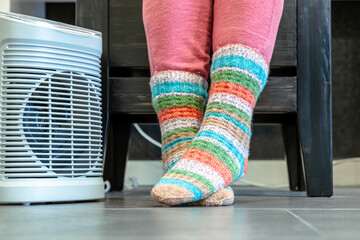 Heating season. feet in socks. woman feet with socks. Room heating with electric heater at home. 