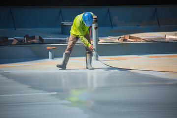 A male worker holding an industrial spray gun used for roof plate tank surface on steel industrial...