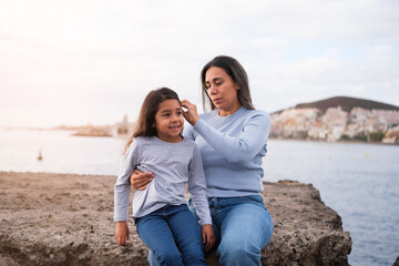 Mother and daughter with great complicity outdoors combing her hair and sharing good times. Concept: motherhood, education