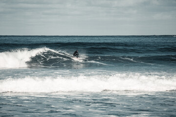 Arctic surfer in Unstad beach, Lofoten, Norway during cold winter time with big waves 