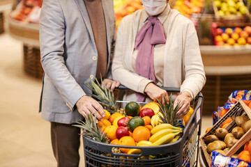 A senior couple shopping fruits at the supermarket. A shopping cart full of fresh healthy fruits.