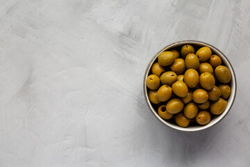 Marinated Green Pitted Olives in a Bowl, top view. Flat lay, overhead, from above. Space for text.