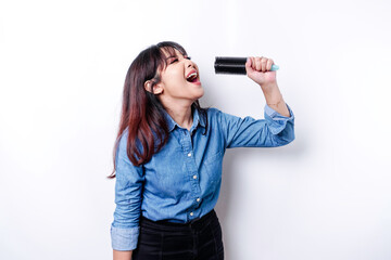 Fototapeta premium Portrait of carefree Asian woman, having fun karaoke, singing in microphone while standing over white background