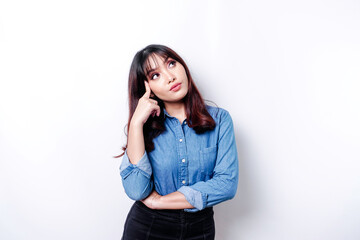 A thoughtful young woman dressed in blue shirt while looking aside, isolated by white background