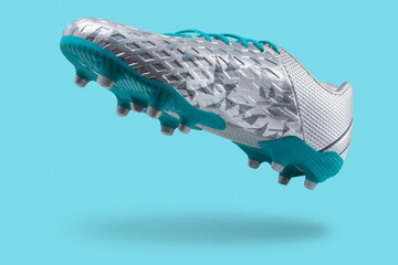Silver football shoes with a turquoise sole, levitate on a turquoise background, concept