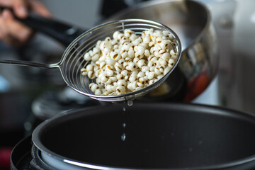 Hot Boiled Job’s Tears millet seed from boiler. White boiled Job’s Tears is highly nutritious cereal healthy fresh organic in salad dish.