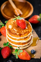 A pile of pancakes with berries and honey. 