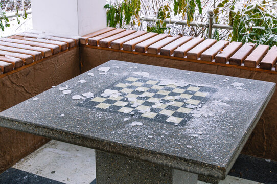 A game of chess. A house in the park for playing chess. A chessboard in the ice in the winter park. Board logic game with chess pieces. The image of a chessboard on a granite surface.
