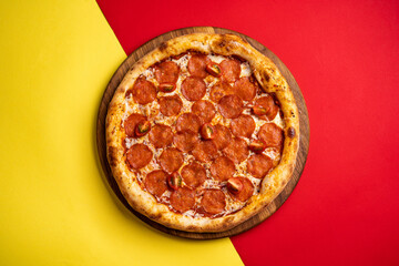 pizza with salami on a board on a colored red-yellow background