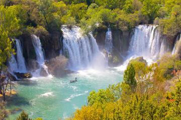 Small boat rowing just under Kravica waterfalls in southern Bosnia and Herzegovina