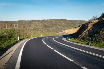 Estada asfaltada  com uma curva à frente a meio de algumas montanhas