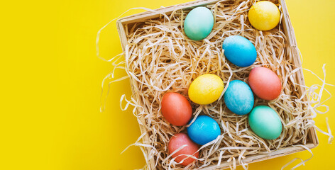 Colorful Easter eggs in basket on yellow background. Family with kids preparing for Easter at home....