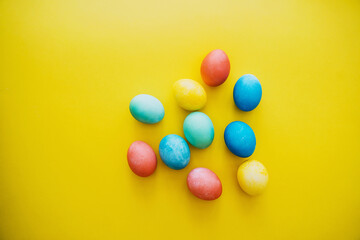Fototapeta na wymiar Colorful Easter eggs in basket on yellow background. Family with kids preparing for Easter at home. Top view, flat lay.