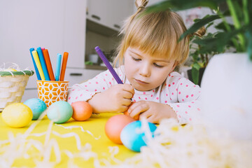Smiling little girl with colorful eggs preparing for Easter Holiday. Kids painting easter eggs. Creative background for preschool and kindergarten. Family traditions and symbols of celebration.