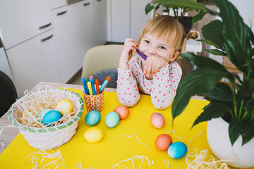 Smiling little girl with colorful eggs preparing for Easter Holiday. Kids painting easter eggs. Creative background for preschool and kindergarten. Family traditions and symbols of celebration.