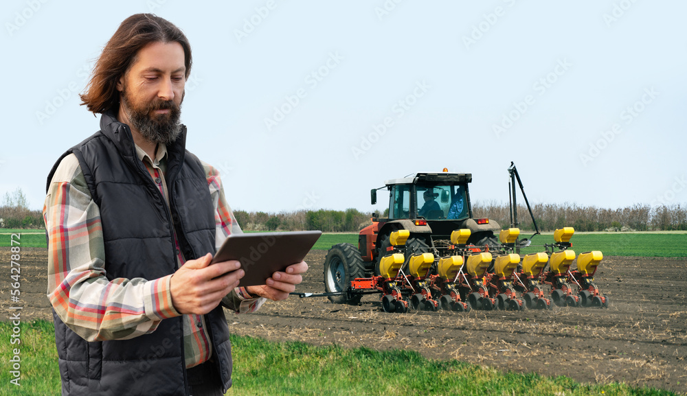 Poster farmer with a digital tablet on the background of an agricultural tractor with seeding machine