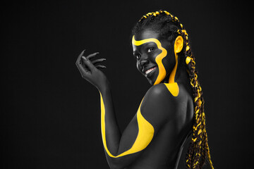 The Contemporary Art Face. Inspiration and idea for trendy magazines. Black and yellow body paint on african woman. An amazing model with makeup and bodyart.