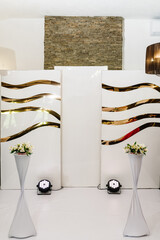 Arch, wall, photo zone, area decorated with a composition of white flowers and greenery in the hall. Golden autumn decor in the banquet area at the party. Decorations in luxury ceremony.