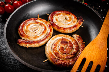 Delicious grilled sausages in a frying pan with fresh tomatoes. 
