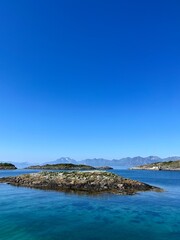 Fototapeta na wymiar Blue calm ocean bay horizon, small rocky islands, blue sky